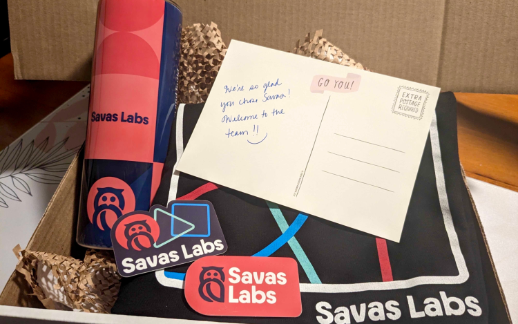 Savas Labs employee welcome box with a t-shirt, post card, tumblr, and stickers