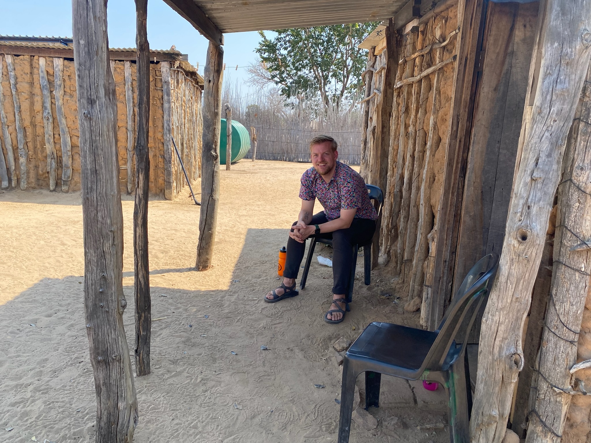 Matt T sitting outdoors under a wooden structure