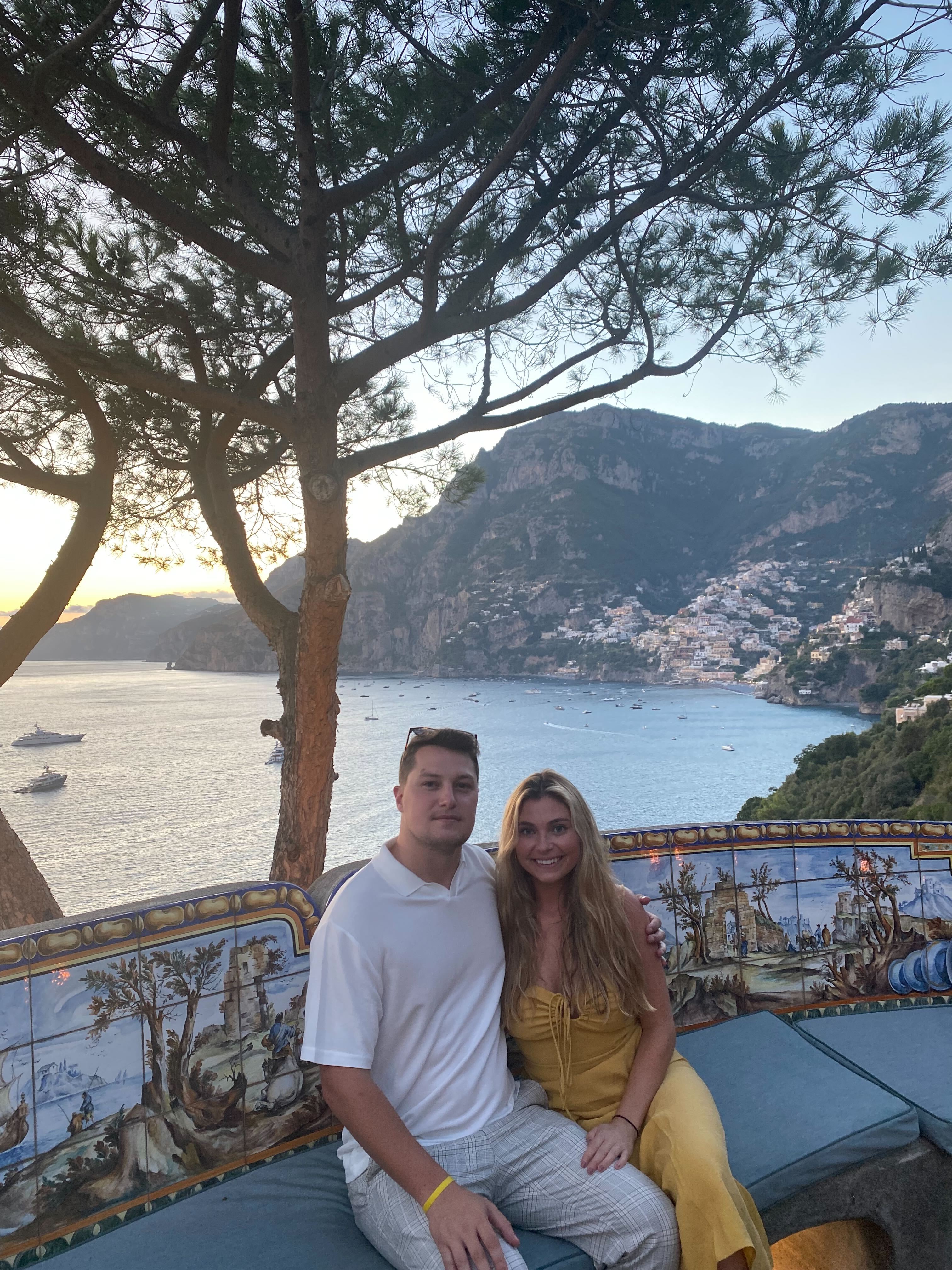 Zakk and female friend sitting in front of a tree and lake