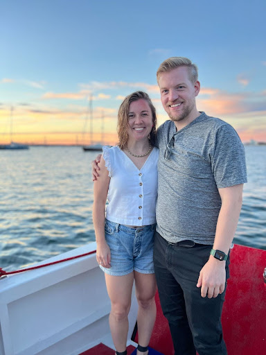 Matt T and spouse standing in a boat in front of sail boats