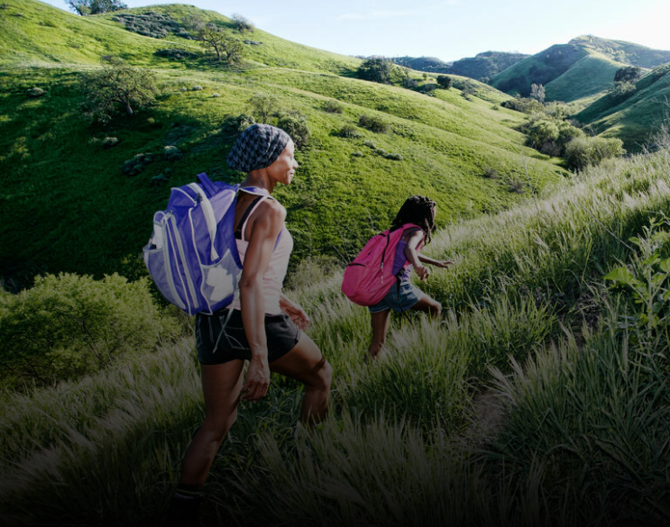 Two women hiking over grassy hills