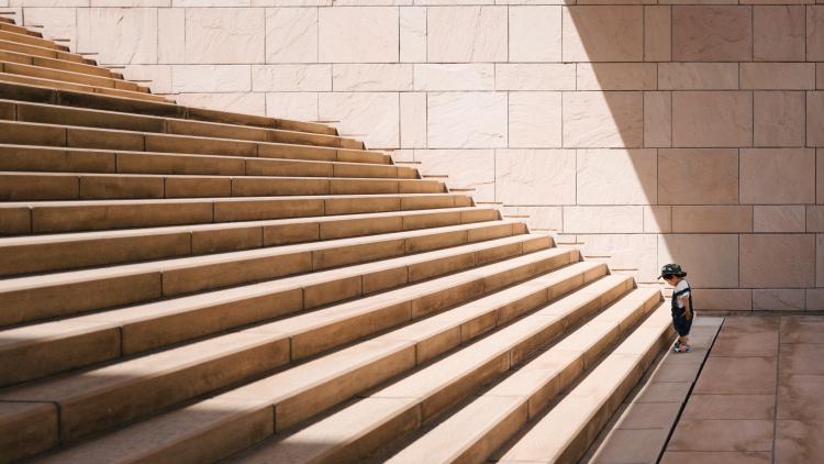 A small child about to ascend a large stone staircase. Photo by Jukan Tateisi on Unsplash.